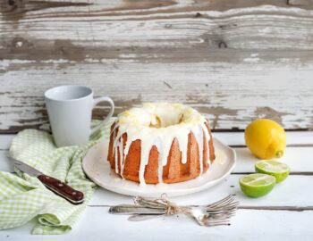 Moist lime and lemon bundt yoghurt cake, white rustic wooden background.