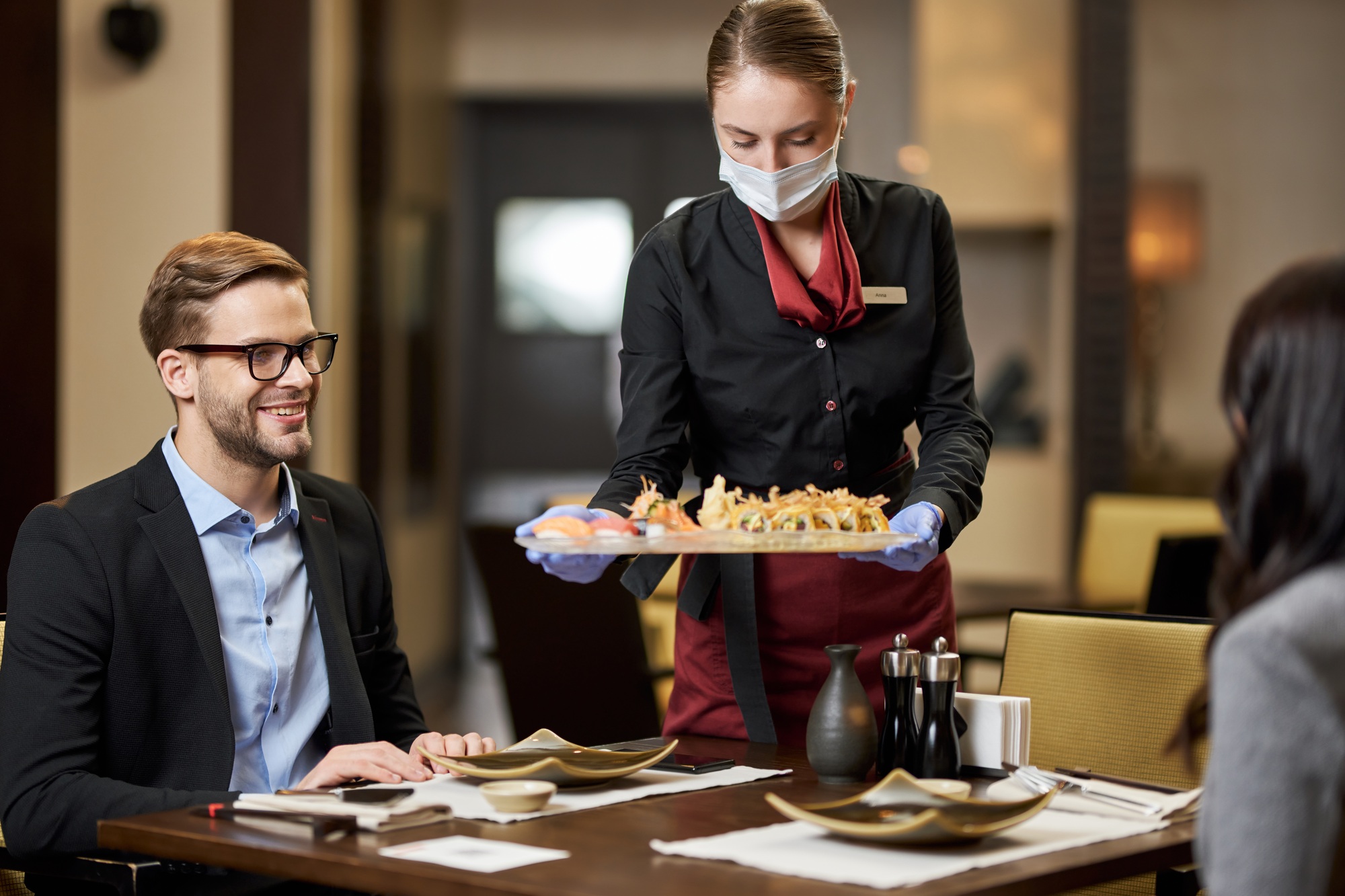 Pleased gentleman and his date being served sushi at restaurant
