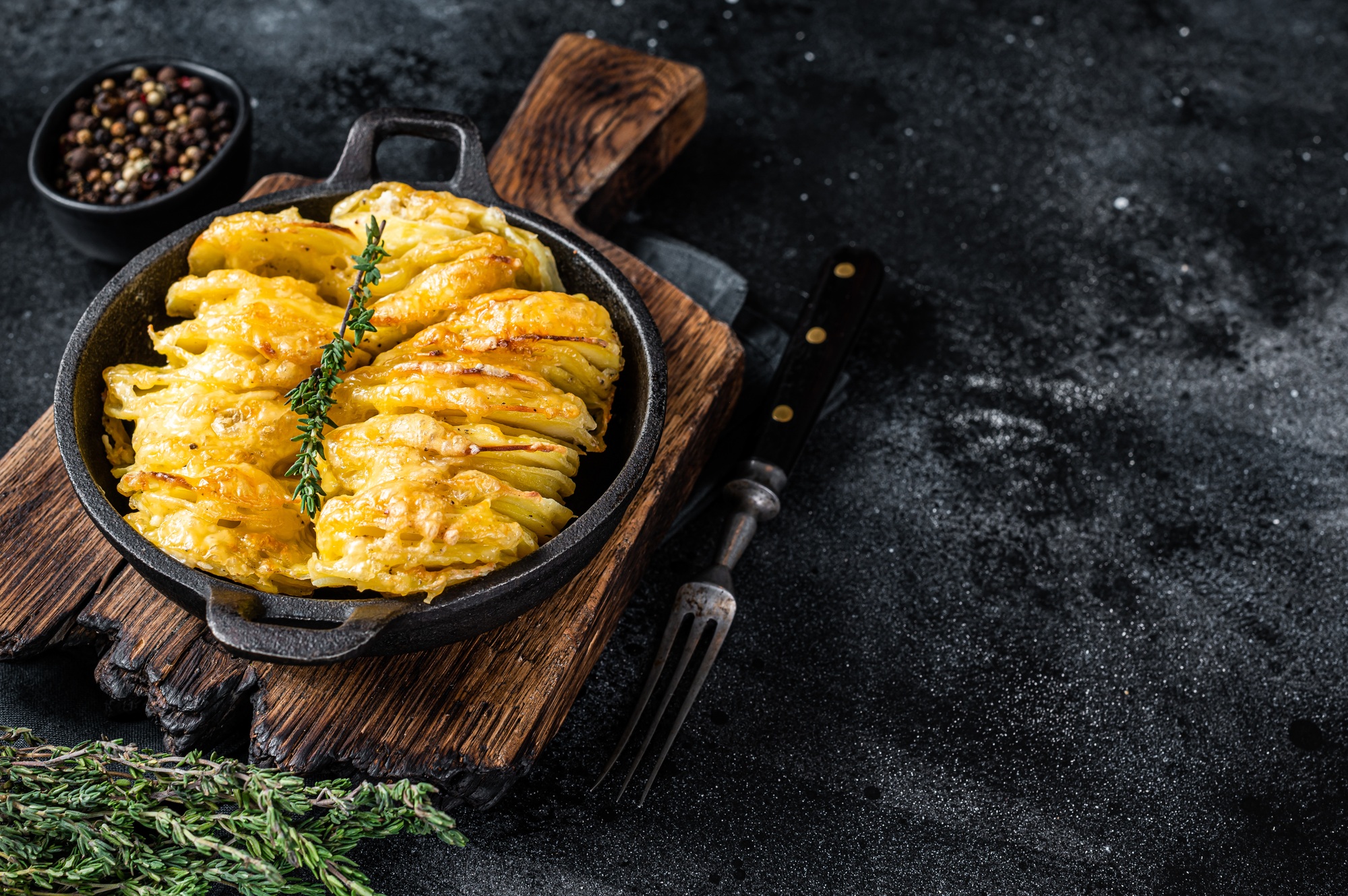 Potato Gratin Dauphinois in a pan. Black background. Top View. Copy space