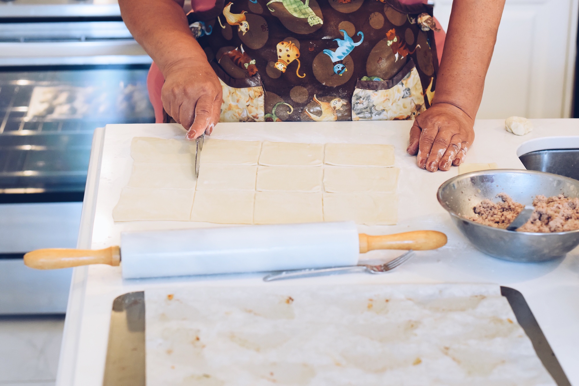 Woman cutting pastry dough with knife to make puff pastries